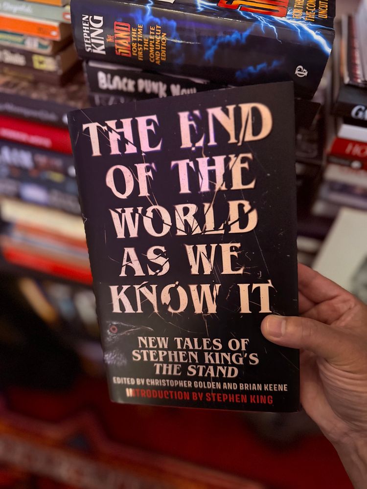 Holding up the front cover of The End Of The World As We Know It: New Tales Of Stephen King’s The Stand Edited by Christopher Golden and Brian Keene