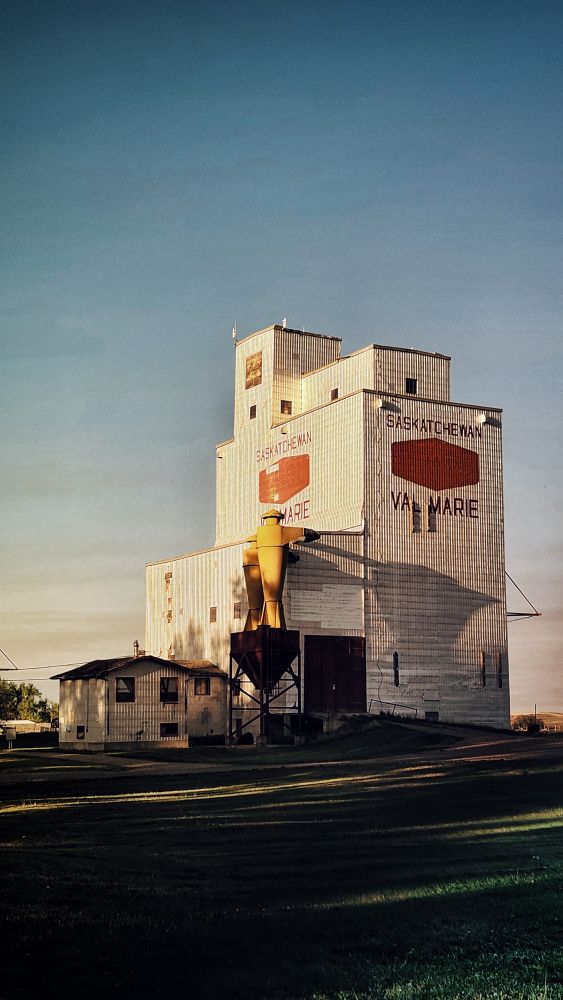 Grain elevator, a multi story metal plates building to store grain. Has red text stating Val Marie and has a small operations hut next to it.