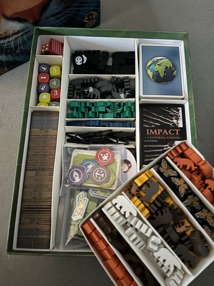 Overhead shot of Endangered with the animal tray removed to show bottom layer.

Left bottom: All game tiles 
Left middle: Player dice
Left top: Orange and black game dice, calendar marker
Middle top: Animal tokens in two trays 
Middle bottom: Animal placards, animal boards, player boards, money, influence cubes, player mini cards and tokens
Right bottom/middle: Animal cards 
Right top: Player cards, reference cards, U.N. cards, campaign cards