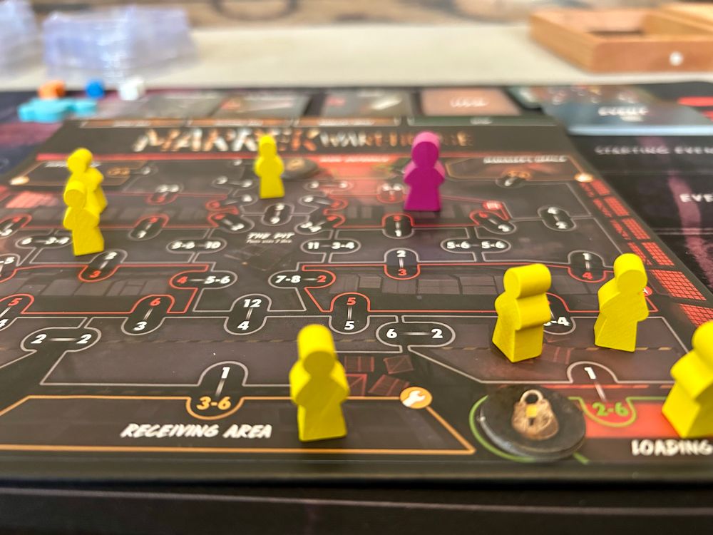 Close up of the Marrek Warehouse location board for Final Girl with 6 yellow Victim meeples and a pink Final Girl meeple.