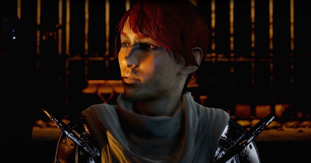 Screen cap of Cyrica, a dwarf Inquisitor in Dragon Age: Inquisition. They have messy short red hair, bright green eyes, and short stubble for facial hair. Their nose is broken and has a large scar on it. A dark bluish-black tattoo goes across their eyes, with two sets of angular lines connecting them across the nose. Cyrica is wearing the default armor and is shown imprisoned at the beginning of the game.