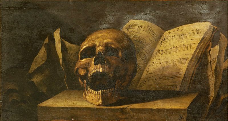 A skull, it jaw open, sits on a plinth in front of a book of sheet music.
