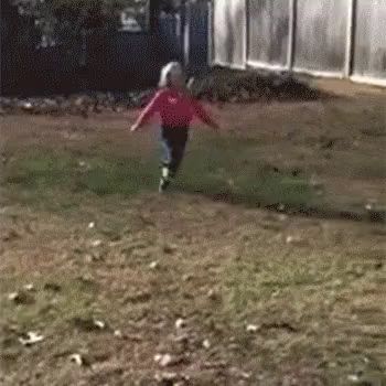 a little girl in a red shirt is running down a dirt path .