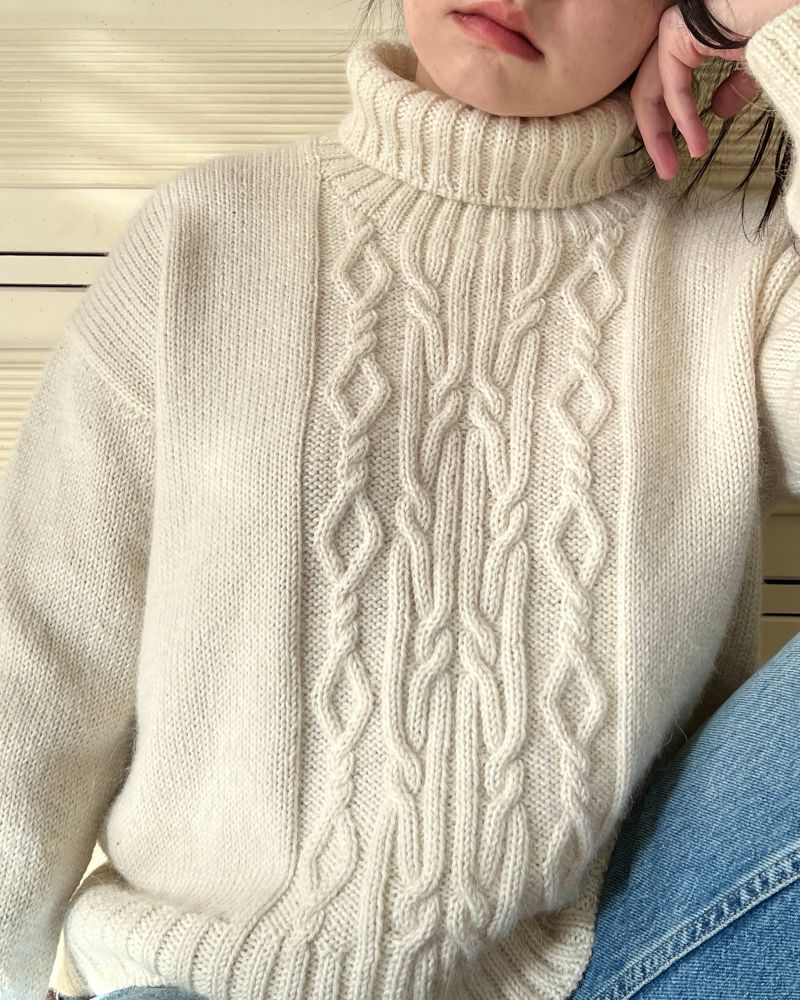 Woman wearing a white turtleneck cabled sweater