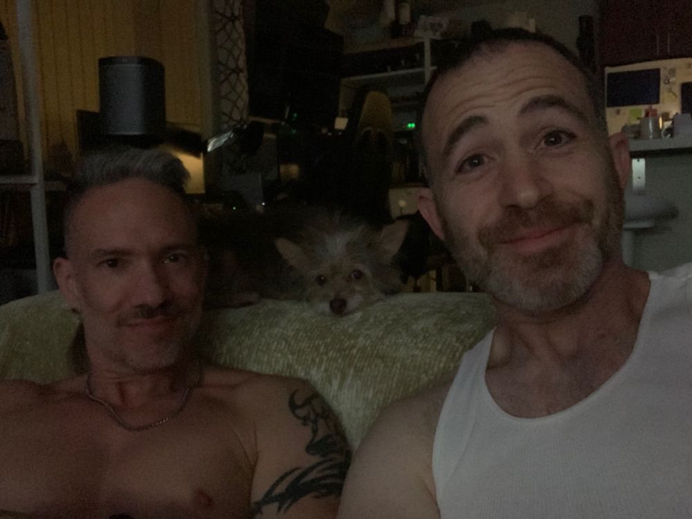 Jay and I sitting on the couch. Brixley perched on the back of the couch resting his head down with his little face visible right between our heads.