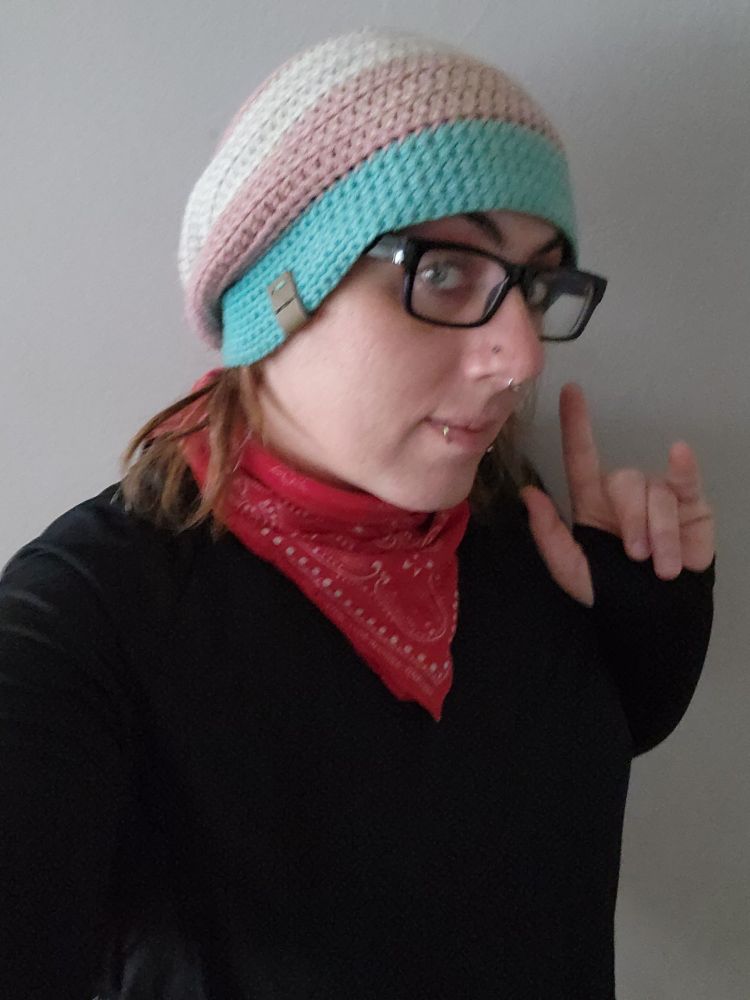 Lila wearing a trans flag hat, a black bandana around her neck, and a black long sleeved shirt