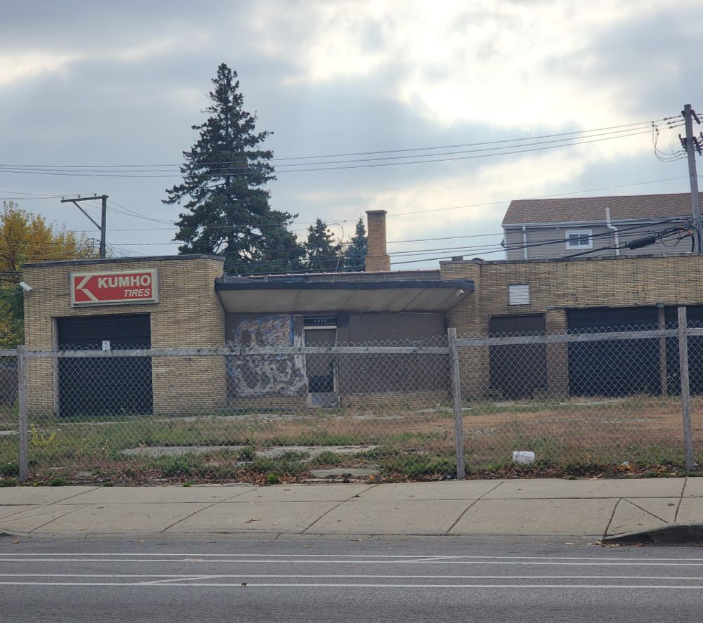 An abandoned Kumho tires location behind a chain link fence 