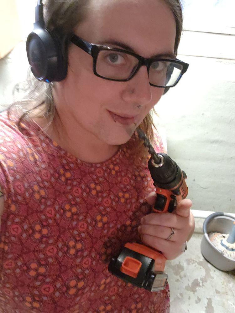 Lila holds a power drill. I'm not sure if she's going for suggestive or intimidating, but she's showing good trigger discipline, so there's that, at least