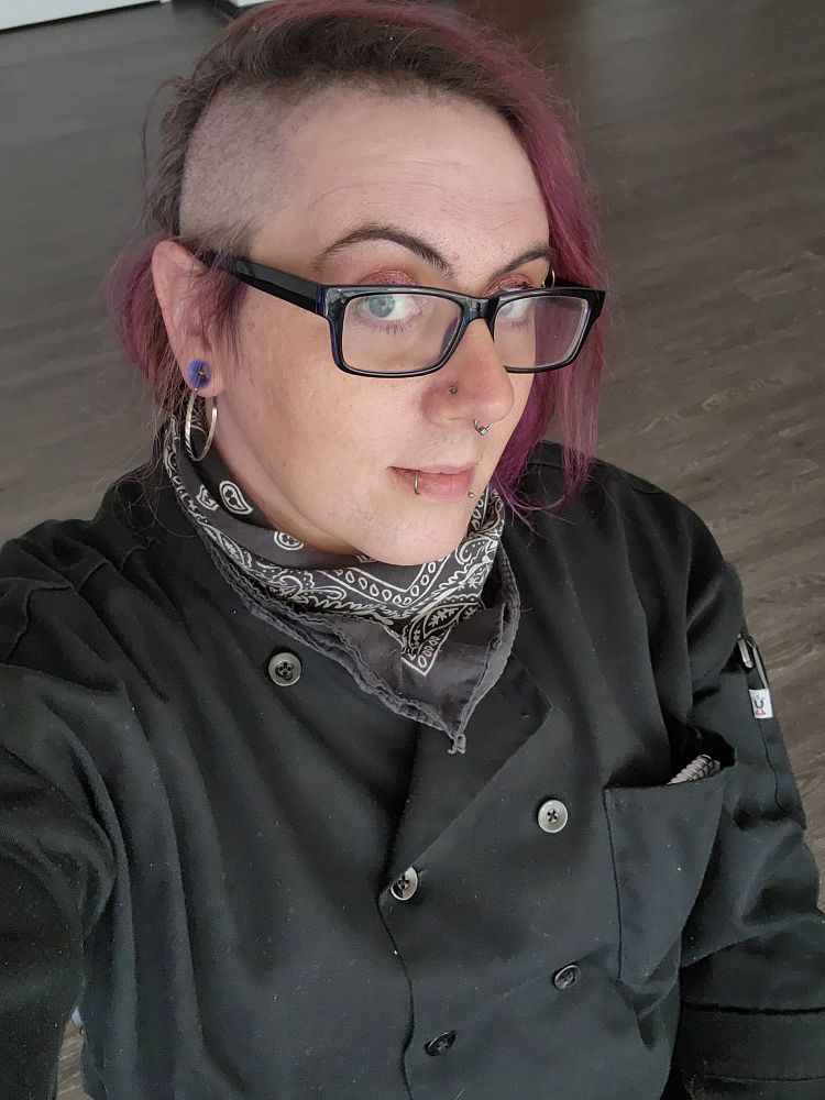 Lila with a fresh side shave and dye job, wearing a chef jacket 