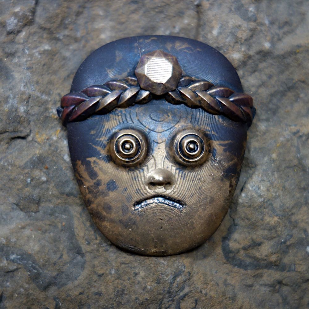 A sculpture of a face in bronze.