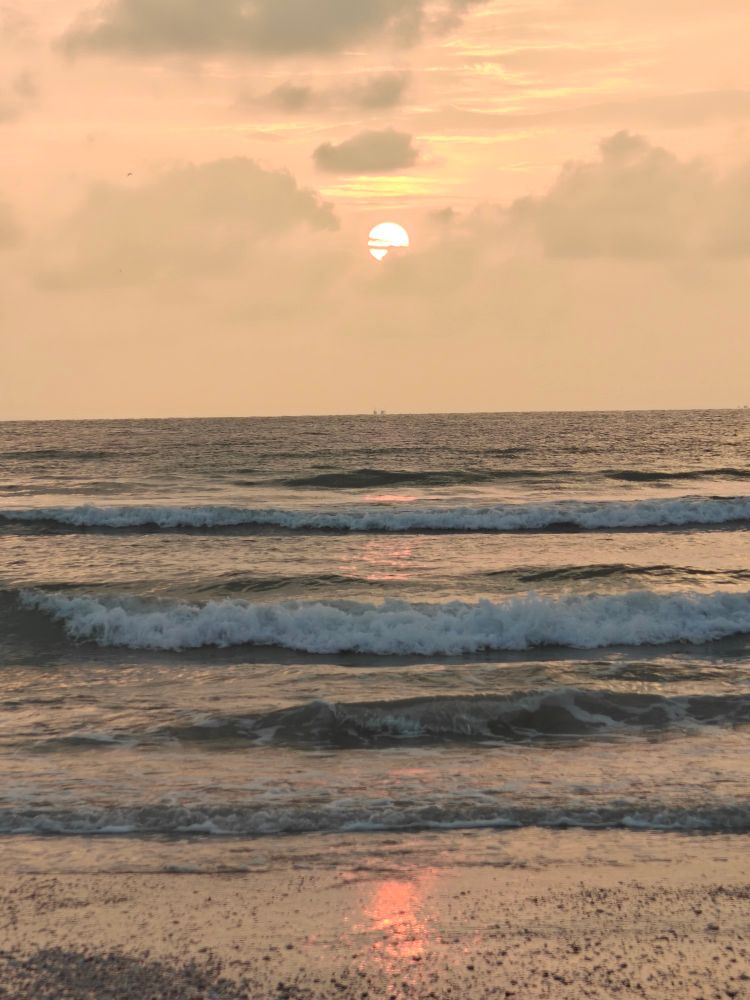 Sunset setting behind sparse clouds over the Arabian Sea 