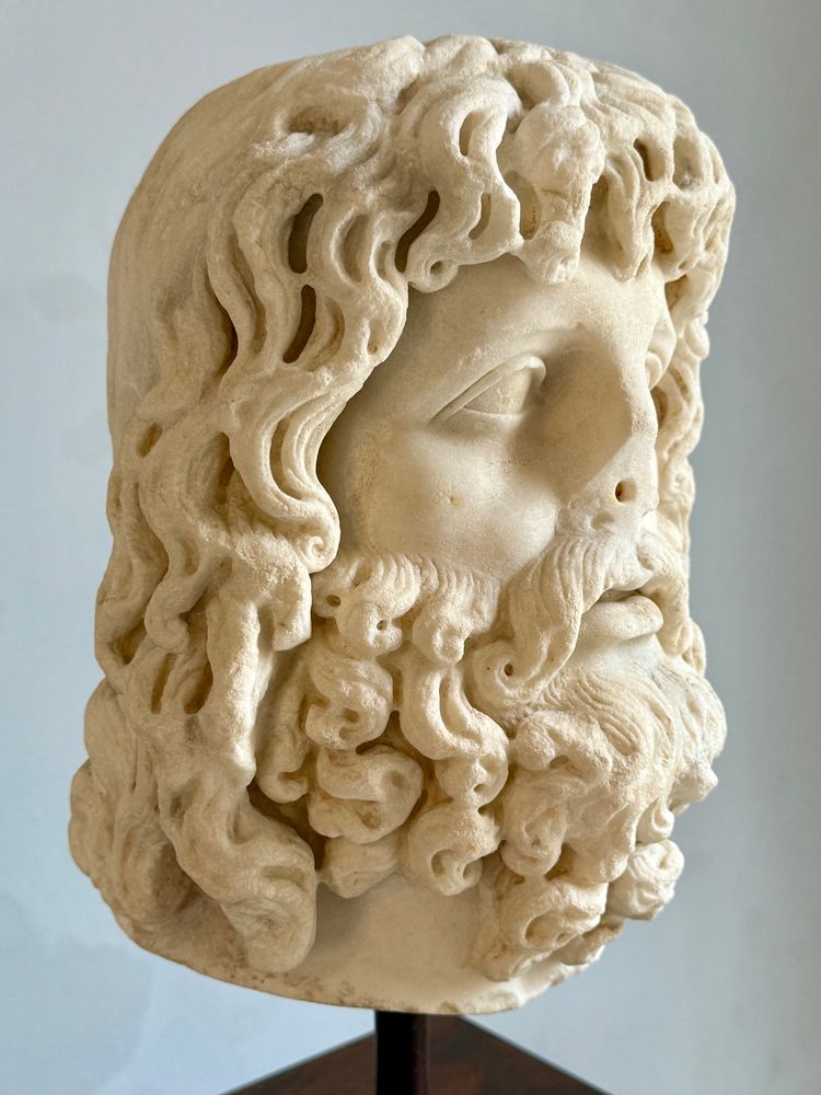 The bust of Serapis with hair and beard curls. 