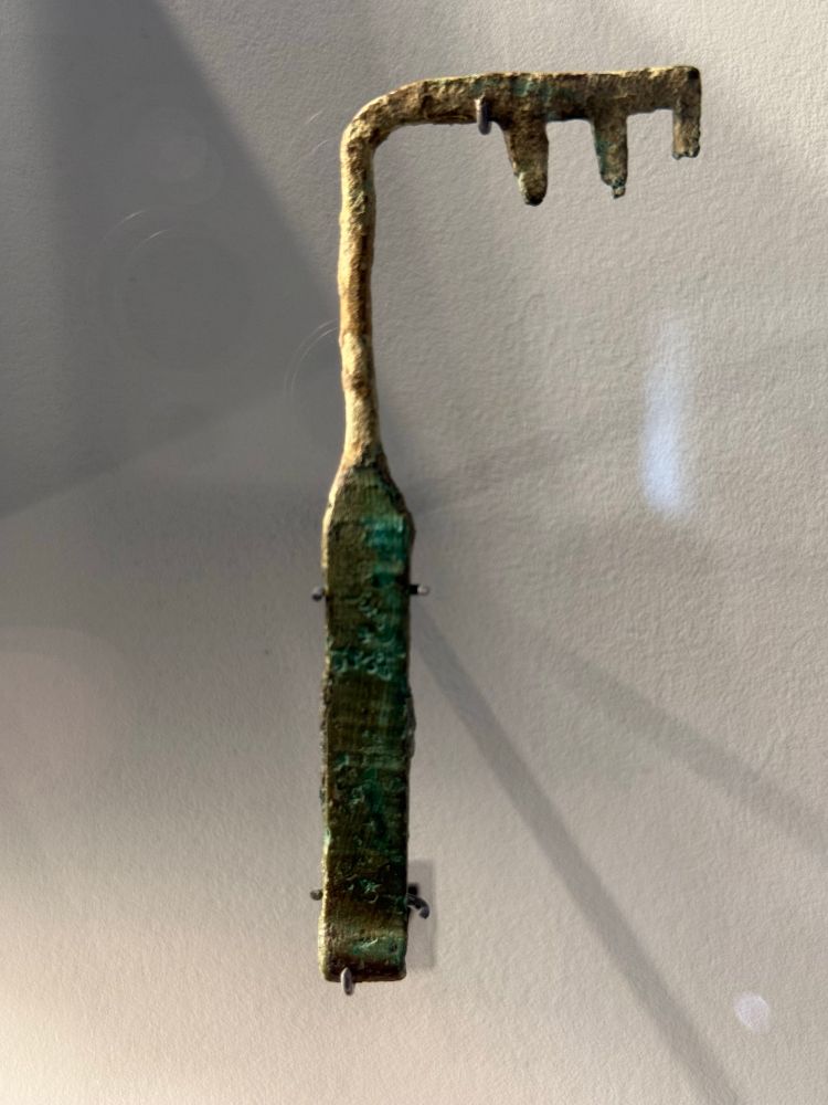 A metal key which has a hooked bit at a right angle with three teeth at the end pointing back towards the handle. 