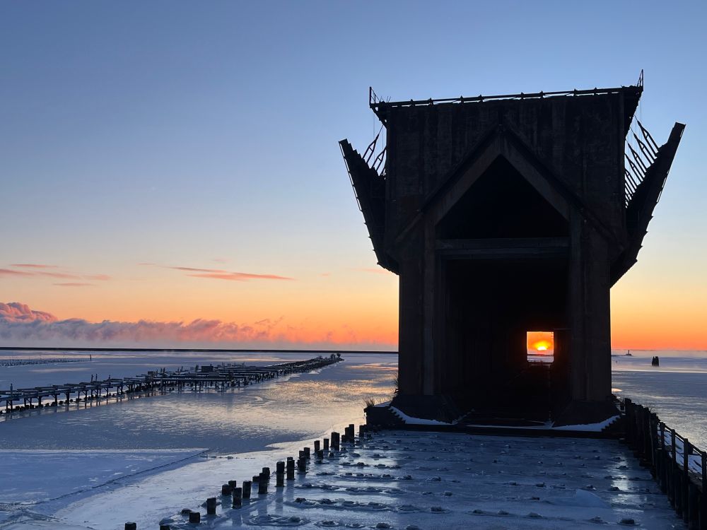 Sun rises behind the Ore Dock in lower harbor in Marquette Michigan. This event, where the sun rises in between the support pillars, happens twice a year and is locally referred to as “Ore Henge”.