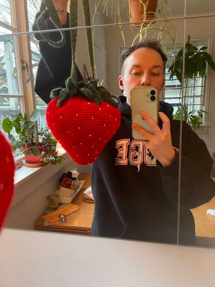 marcel holding up crochet bag shaped like a strawberry