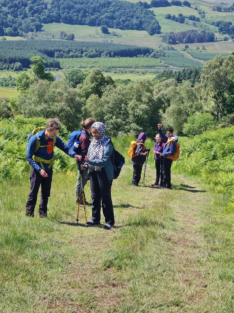 A group of hikers on a grassy track with trees in the background.