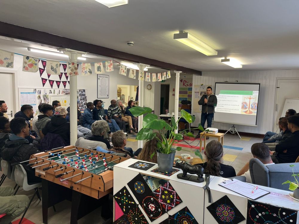 A Community InfoSource outreach worker delivering a presentation in front of a group of refugees and people seeking asylum.