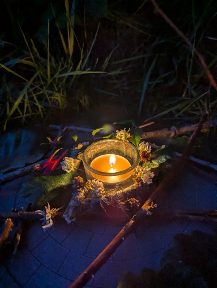 The same ritual spread, but now it's dark and the candle burns bright in the night.