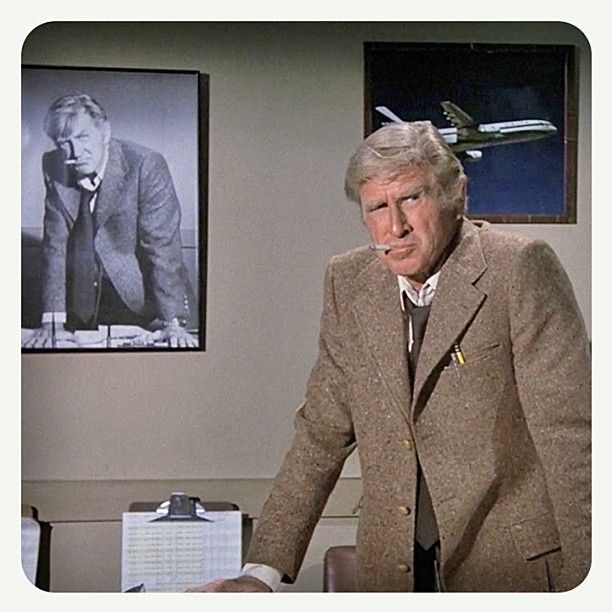 Steve McCrosky standing in front of a photo of himself in a similar pose, from Airplane!