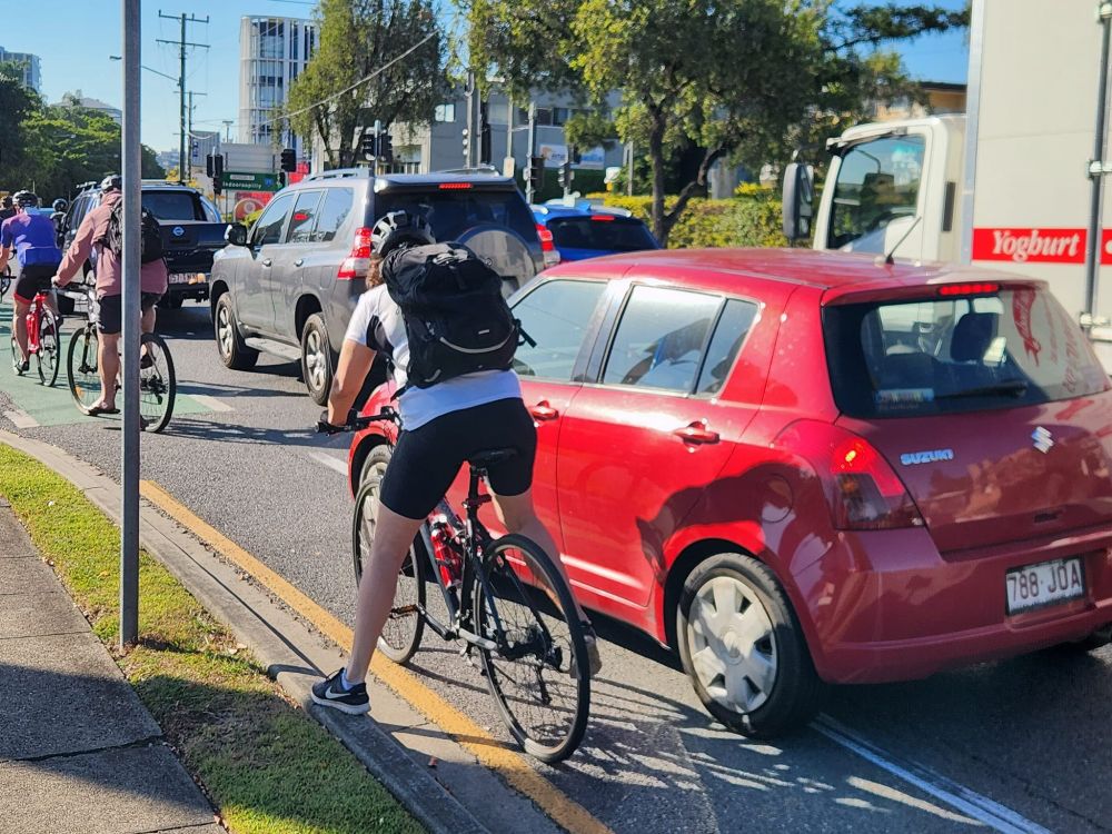 Cyclist trying to squeeze past an errantly stopped car obstructing the painted bike lane on Sylvan Road.