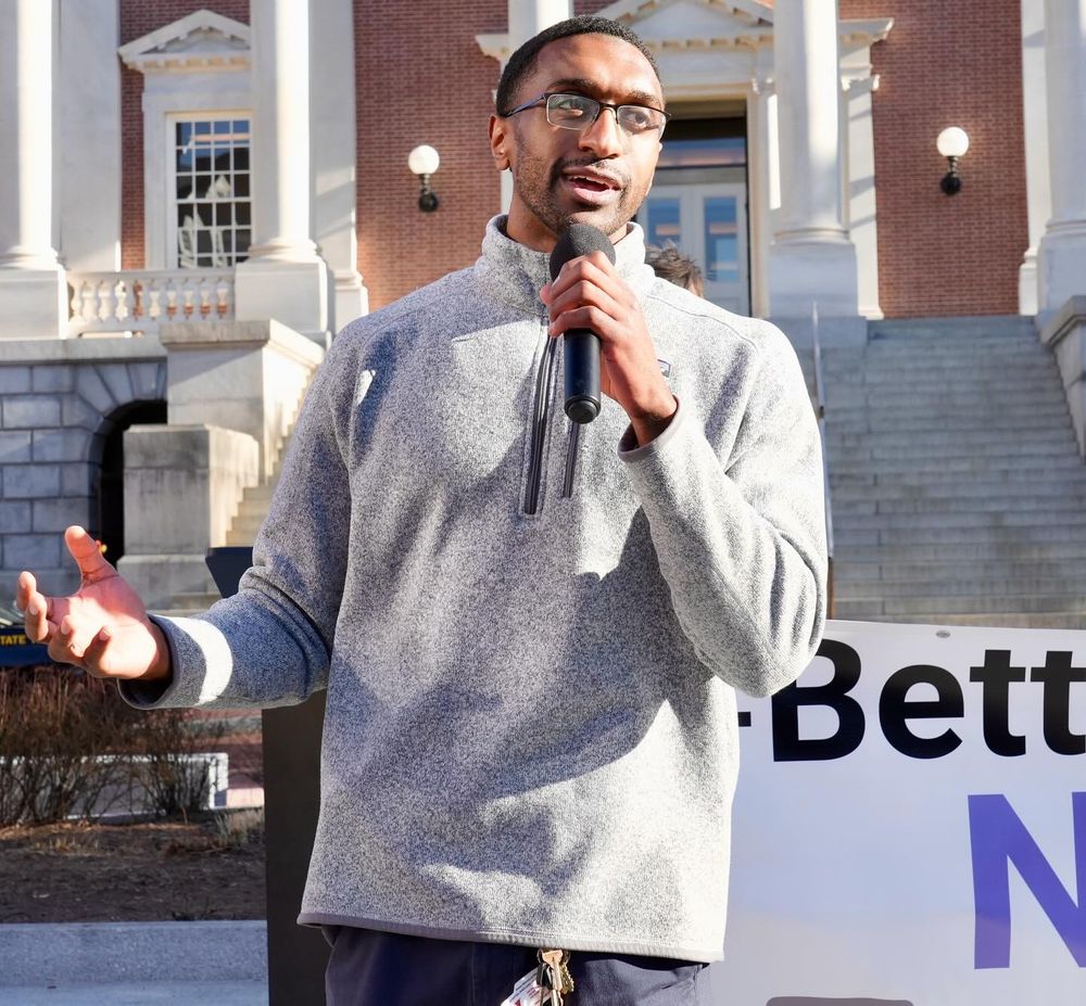 A photo of Collington Square Elementary Middle School teacher Jordan Jones speaking about his experiences using public transit in Baltimore compared to other countries he visited as a former professional basketball player. Jordan is speaking outside the Maryland State House on February 4th, 2025 talking to Transit Rider Rally participants.