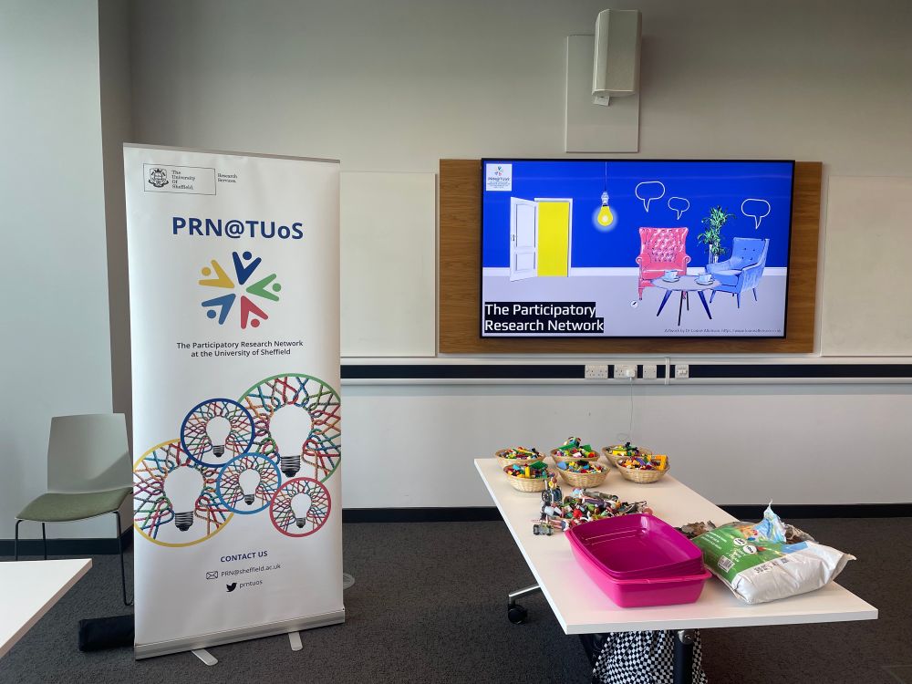 A table with Lego and sandboxing material _ sign and power point saying the participatory research network 