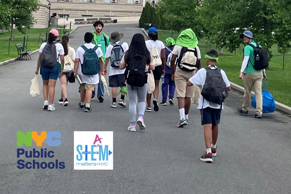 A group of students in summer clothes and backpacks tour an outdoor garden