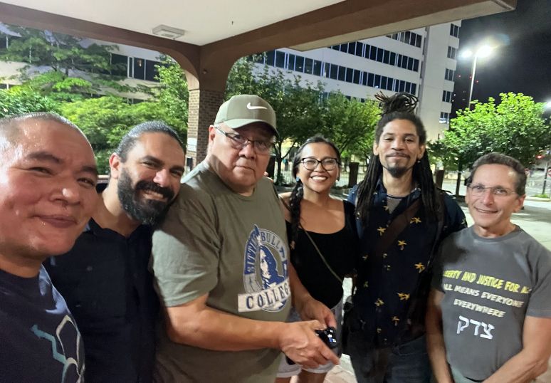 Six people pose for a photo outside of a convention center.