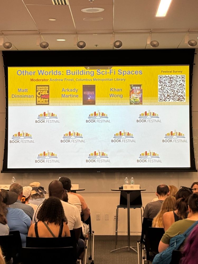Panel backdrop featuring the title Other Worlds: Building Sci-Fi Spaces with the author names Matt Dinniman, Arkady Martine, and Khan Wong, with their book covers