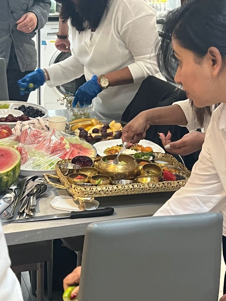 A kitchen table full of platters of fruit and other offerings that are being prepared for a Dana in the London Buddhist vihara