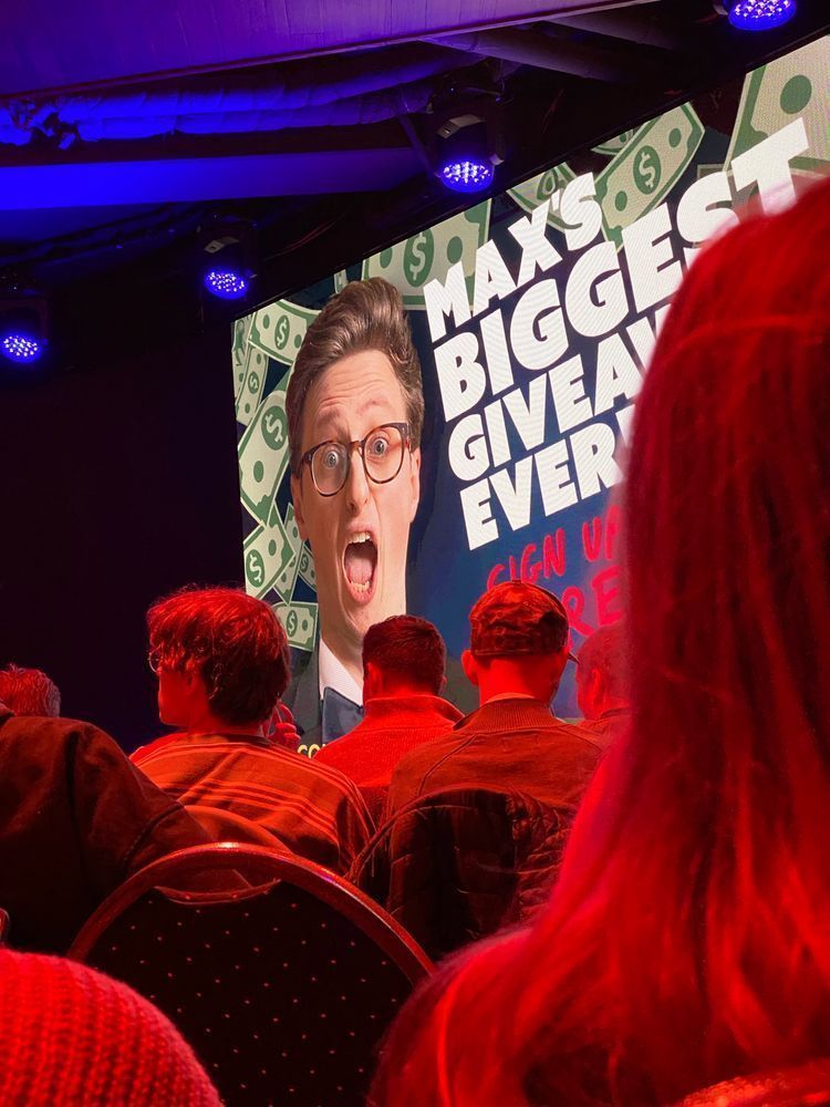 A photo of a stage where Max Fosh played his show Loophole. In the background there is a slide with Max's face and the text "Biggest giveaway ever"