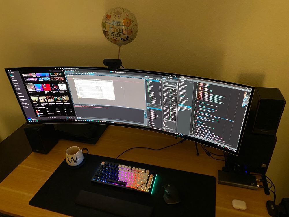 Am image of a clean and cozy desk setup of a gamedev with ultra wide Samsung screen, mechanical keyboard and a coffee. There is Godot game engine open