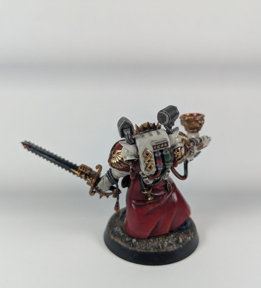 La misma miniatura pero desde atrás. Se puede ver la mochila donde lleva su propia versión del caduceo y los artefactos para realizar las inyecciones y extracciones que se realizan con una especie de extensión que sale del brazo donde sostiene la copa.