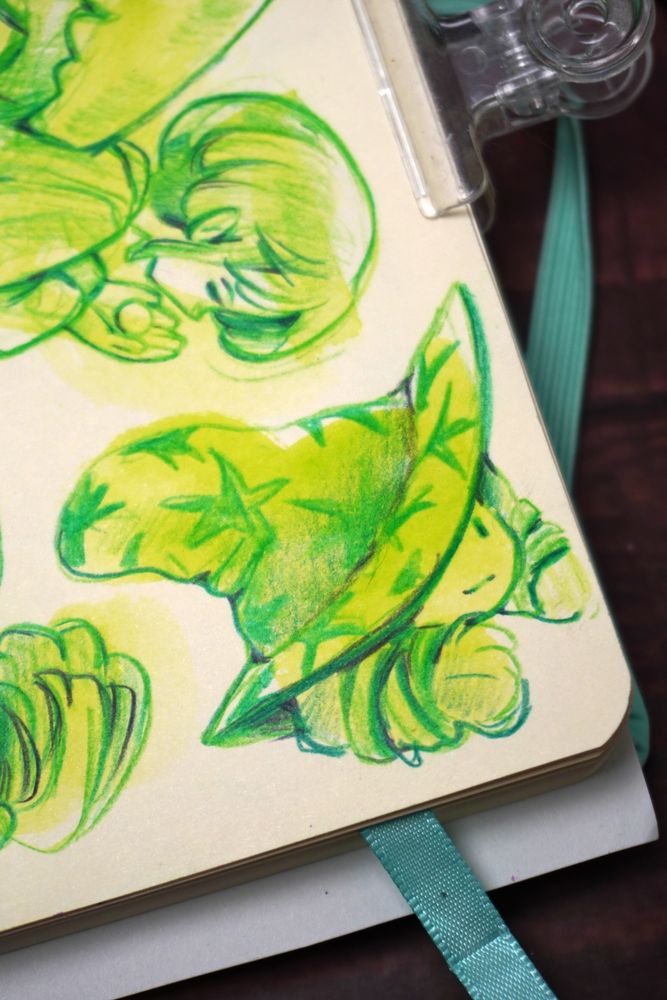 A close-up on a sketchbook page showing a green sketch of a happy witch wearing a large, pointed, star hat