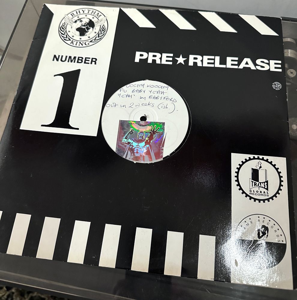 A pre release 12” vinyl record of the Baby Ford classic Oochy Koochy FU Baby Yeah Yeah. The hand written label says it is ‘out in two weeks (ish)’, and has a holographic Magneto sticker on. The track was released on Rhythm King with Trans Global Records and Flame Records and their logos are on the black and white sleeve. It’s in the Kat Five record collection 😺