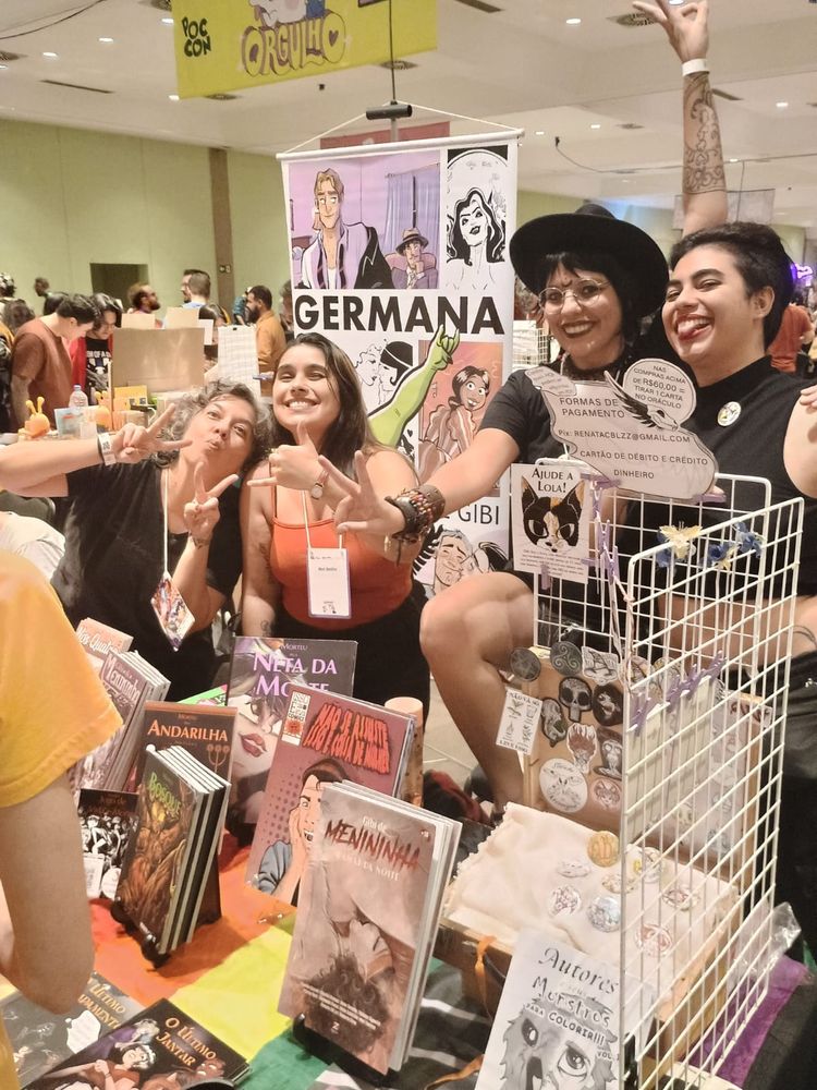 Quatro pessoas na feira poccon, atrás da mesa com quadrinhos expostos