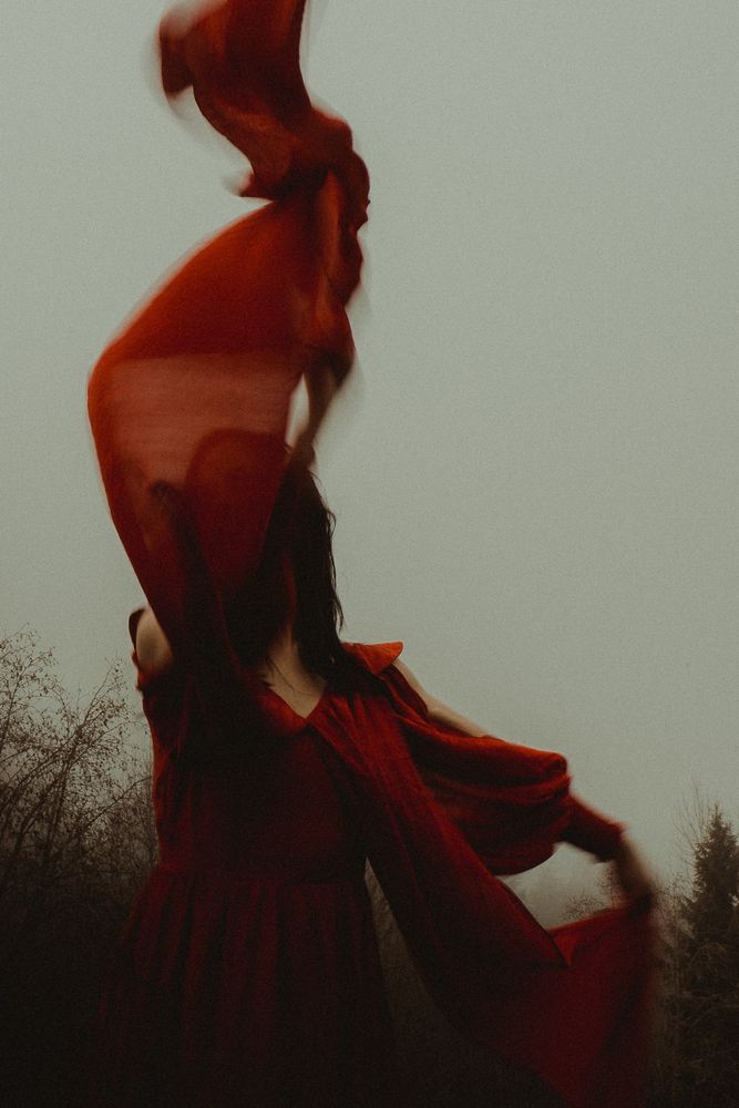 Color image of a woman in red dress with a cloudy moody feel. 