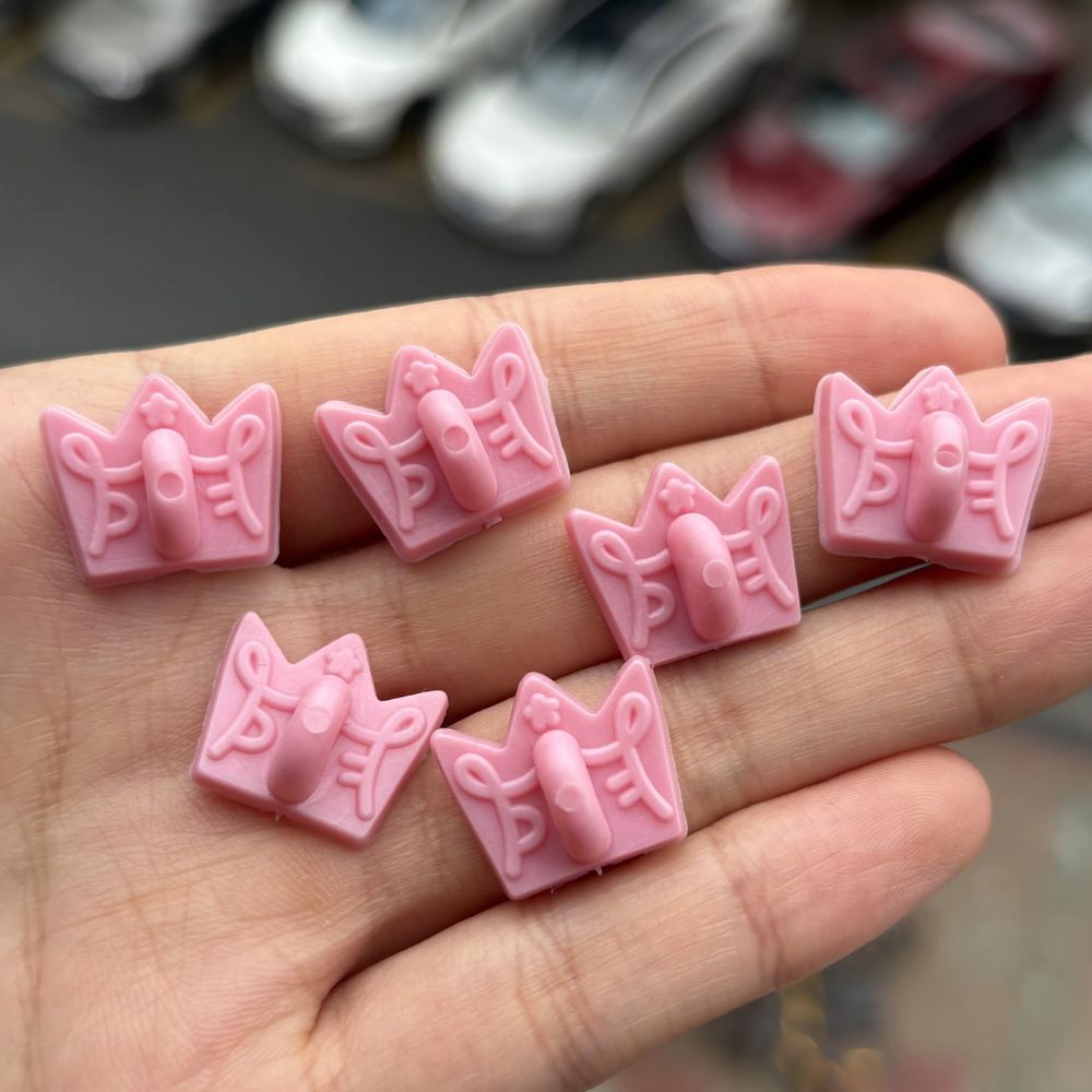 Image of pink rubber pin backings that are crown shaped with the Princefizz Art Logo embossed on them.