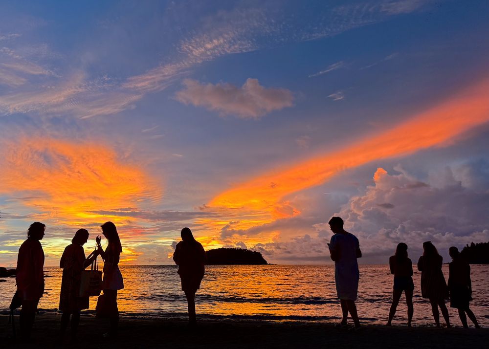 A group of people enjoy the sunset from Kata Beach, in Phuket, Thailand.