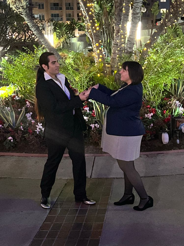 Outdoor night photo. Me in Makoto Makimura from Yakuza 0 cosplay, holding hands and looking at a Y0 Majima cosplayer.