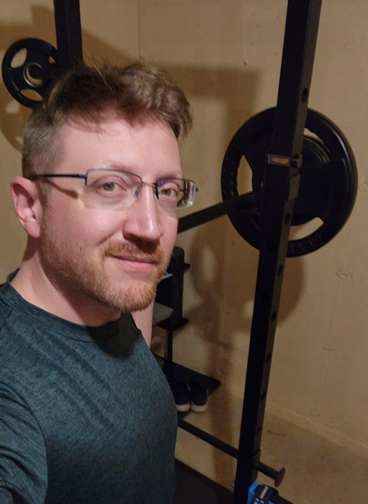 A man standing in front of a squat rack 