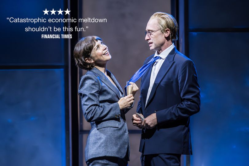 A woman is standing holding a champagne flute and smiling as she pulls a man's blue tie out of his suit jacket. Above them it reads '4 STARS "Catastrophic economic meltdown shouldn't be this fun." Financial Times' 