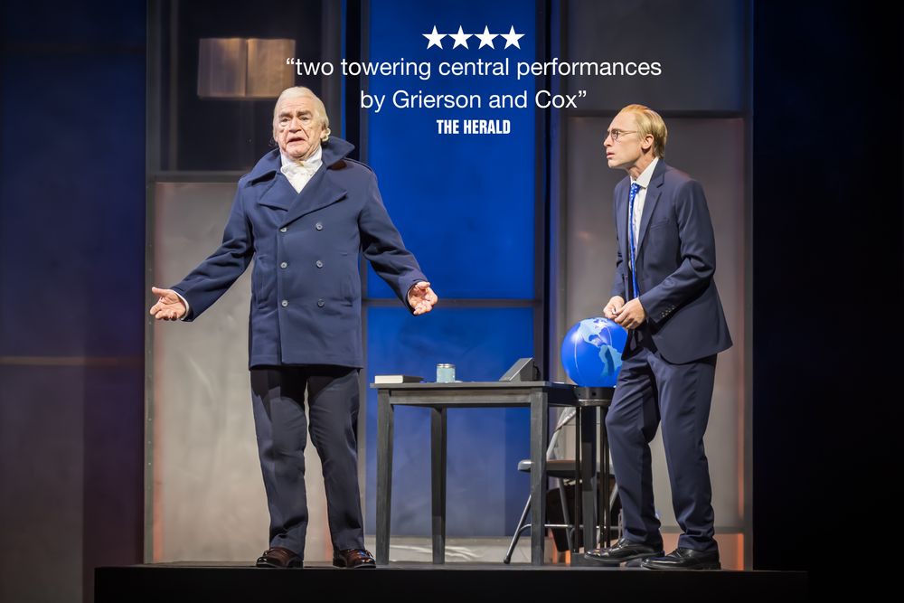 A man with a 17th century style wig is standing with his arms open. Next to him is a man looking panicked. Between them it reads '4 STARS "two woering central performances by Grierson and Cox" The Herald' 