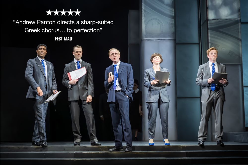  5 people in grey suits with blue ties look off into the horizon, facing out towards the camera. Behind them are tall pillars with projects of the interior of a bank on them. Above their heads it reads '5 STARS, "Andrew Panton directs a sharp-suited Greek chorus... to perfection" Fest Mag' 