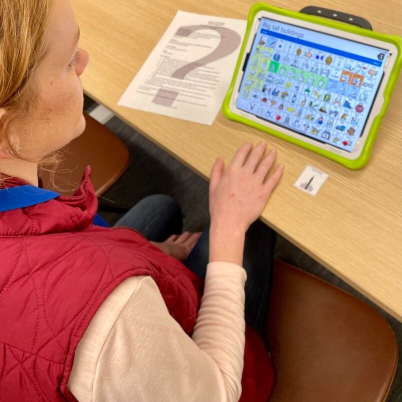 Teacher doing hands-on practice with a speech generating device with a Game Time game. 