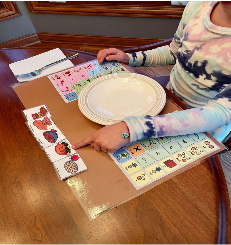 Child pointing to a communication symbol for "turkey" on a communication placemat.