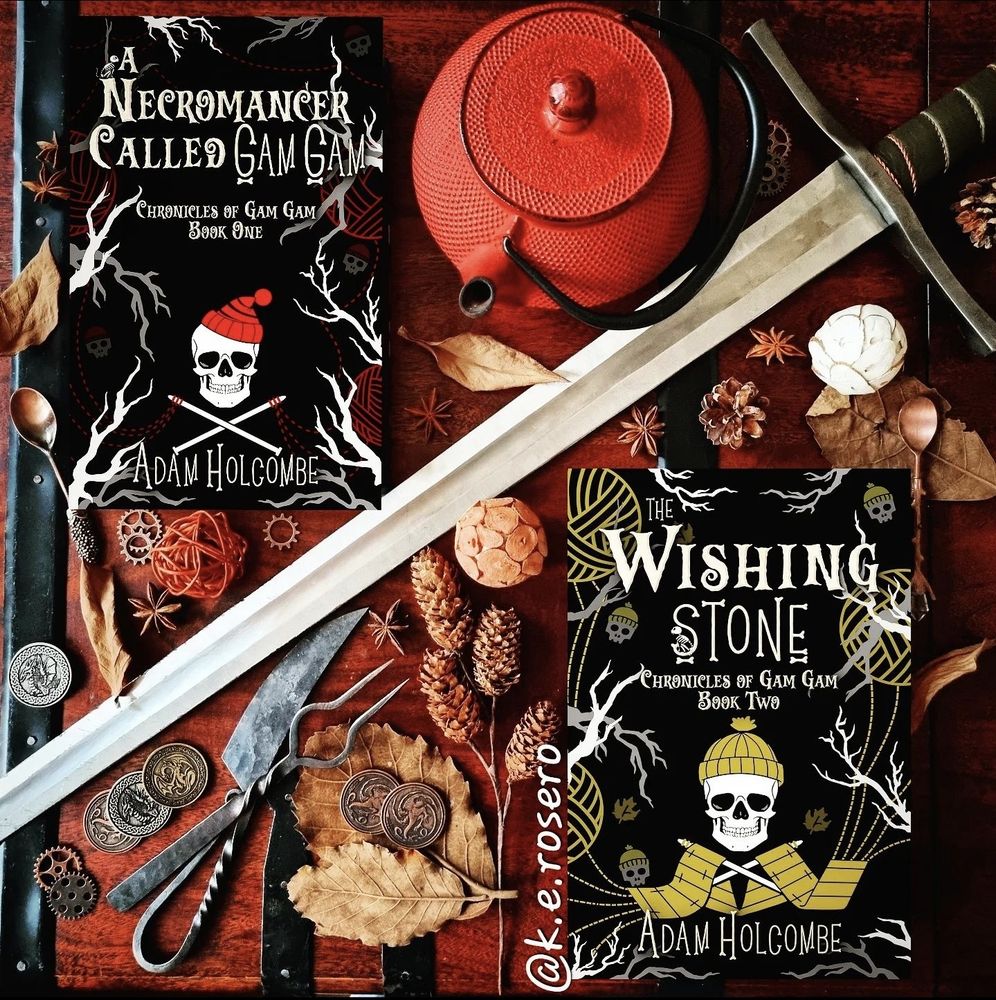 Two novellas, "A Necromancer Called Gam Gam" and "The Wishing Stone" by author Adam Holcombe, positioned around a longsword
