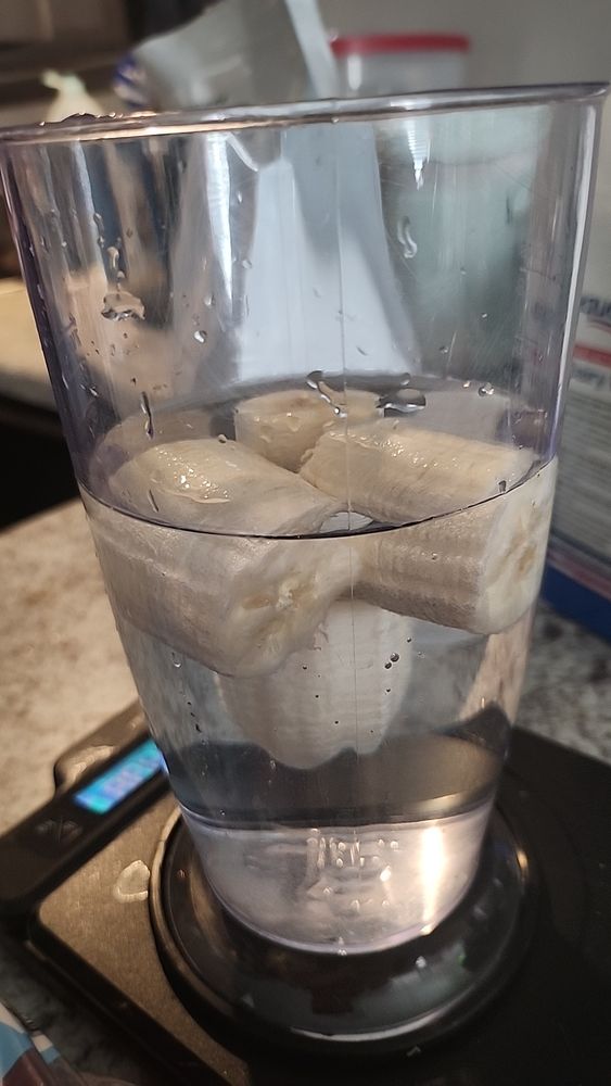 Cut up bananas suspended in a plastic glass of water