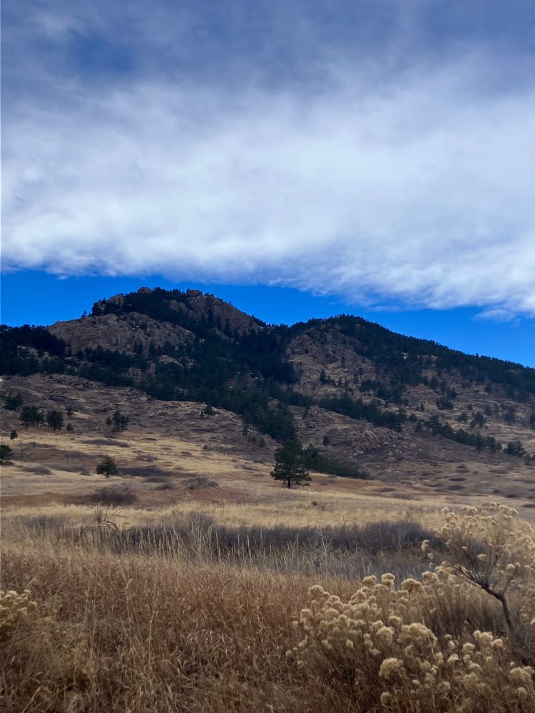 Landscape of a small mountain/rock with blue skies and clouds behind it 