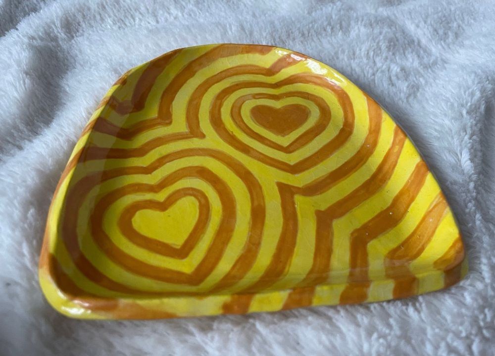 ceramic dish glazed with a yellow and orange heart pattern, expanding outward 